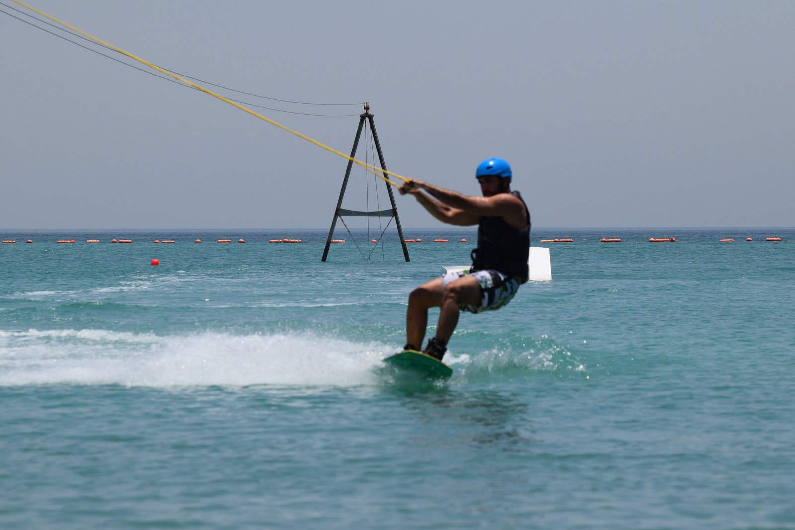 Rider being pulled by the cable tower across turquoise water at Bahrain Wake's cable park in Durrat Al Bahrain